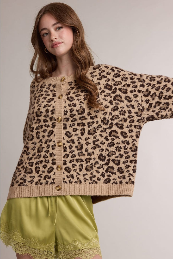 Woman wearing a camel leopard print button-up cardigan sweater with tortoiseshell buttons