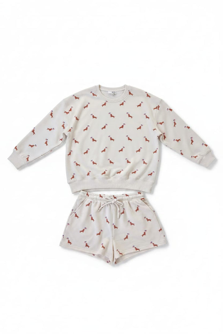 White sweatshirt and shorts set with small pattern on a hanger against a dark background